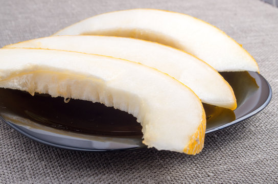 Natural pieces of yellow melon on a black plate