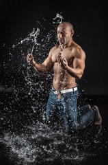 Fototapeta premium very muscular handsome athletic man striking with a hand on wate