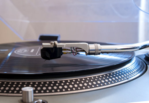 Close up of a turntable needle head playing music from an lp.  (shallow focus).