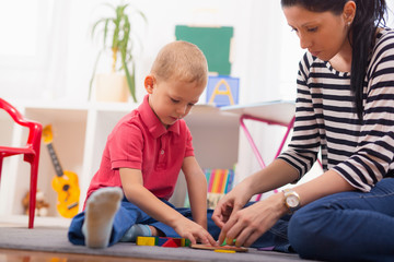 Child boy and mother playing with educational toy