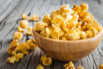 Popcorn in wooden bowl on wooden table background, selective focus, rustic style