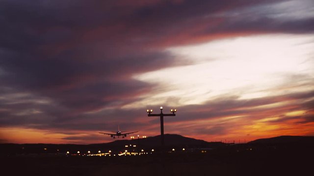 Amazing sky. A big plane is landing at the dusk, close up view. Airport lights, summer evening. Italy, no people around, airport lights on the background.