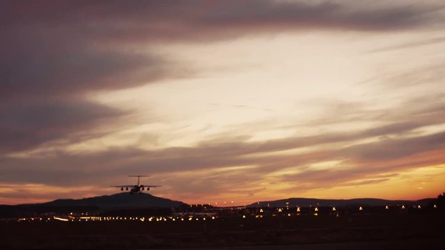 Footage of a 4 engine jumbo jet plane landing in shining small airport. Airport lights on the background. Outside shooting, camera stabilizer shot.