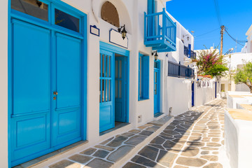 Typical white Greek houses with blue doors and windows on street of beautiful Mykonos town, Cyclades islands, Greece