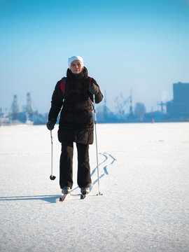 Toned image of an adult woman going skiing on snow crust against the clear sky