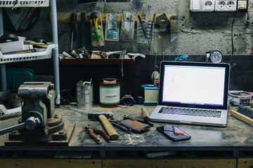 Above view of used hammer,pliers and chisel with laptop and smartphone on metal table
