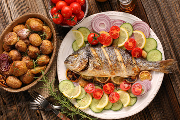 Grilled fish with roasted potatoes and vegetables on the plate