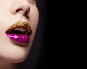 Closeup of woman lips with gold glitter lipstick and violet shiny lip gloss. isolated on black background. Cosmetic makeup image. 