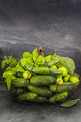 Fresh green vegetables in a basket on a dark stone background.