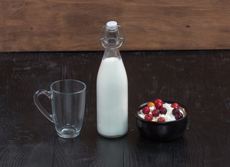 bottle with milk and cottage cheese with berries on rustic table