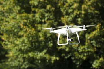White drone quad copter with summer park
