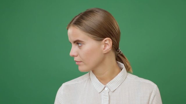 Close up young sad woman in white shirt turning away the face, green screen background