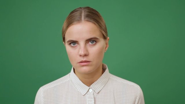Close up young woman in white shirt taking umbrage and turning away the face, green screen background
