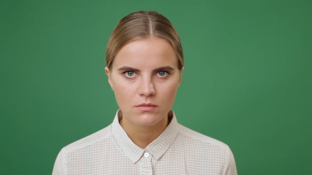 Close up young angry woman in white shirt, green screen background