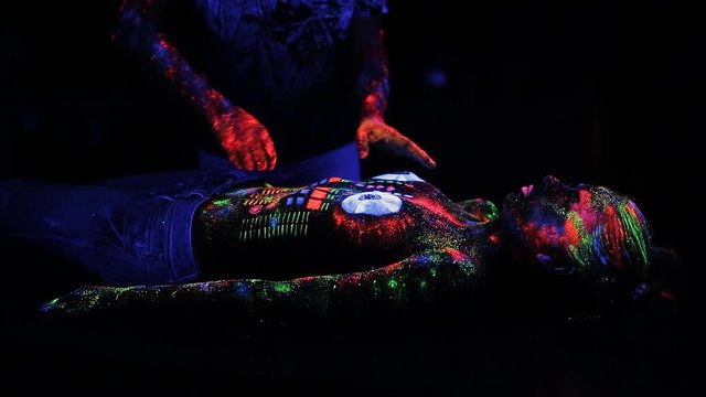 DJ controls, painted with a fluorescent powder on the body of a naked girl, decks