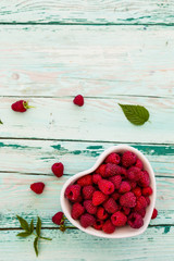 Fresh raspberries in bowl on wooden background with space for text.