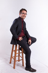 Man smiling at the camera and sitting on a stool