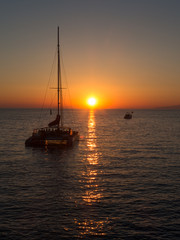 Sunset at sea with yacht on horizon - Oia, Santorini