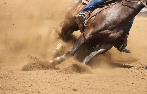 A barrel racing horse skids around the corner throwing up dirt.