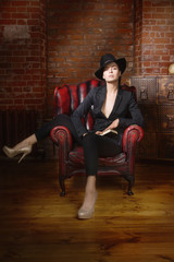 Obraz premium Elegant fashionable woman wearing black suit and hat in a vintag