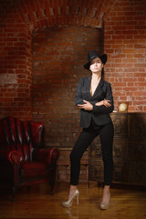 Elegant fashionable woman wearing black suit and hat in a vintag