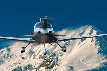 Privat plane or aircraft flight above winter mountains