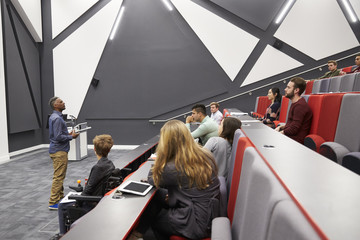 Man lectures students in lecture theatre, front row seat POV