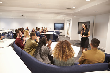 Female teacher addressing university students in a classroom