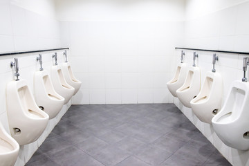 White urinals in men's bathroom, toilet room.