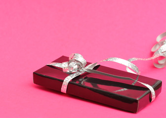 A black gift box decorated with a silver ribbon 