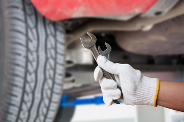 Car mechanic holding wrench at the car repair garage