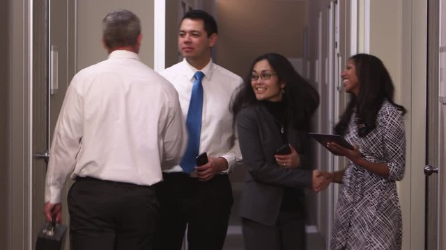 Office coworkers shaking hands in hallway