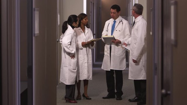 A group of doctors talk as they walk down a hallway together