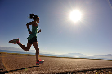  young fitness woman runner running on sunrise seaside trail