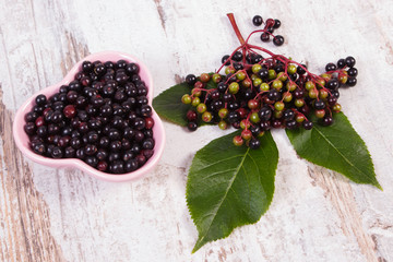 Fresh elderberry with leaf in glass dish on old wooden background