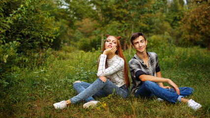 Naklejka na ściany i meble Loving couple teens sitting on the lawn.