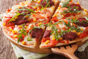sliced pizza with shrimp, salami, cheese and arugula close-up. horizontal

