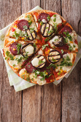 pizza with eggplant, salami and mozzarella close up on a board. Vertical top view
