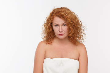 Picture of begging mature or senior woman with red hair looking at camera while posing isolated on whte background in studio. Emotions concept.