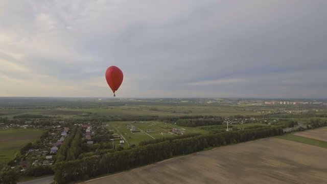 Red balloon in the shape of a heart.Aerial view:Hot air balloon in the sky over a field in the countryside in the beautiful sky and sunset.Aerostat fly in the countryside. 4K video,ultra HD.