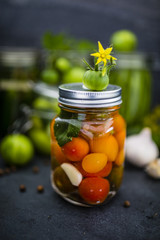 Jar of canned tomatoes and cucumbers jars in background.