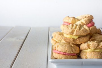 Mixture of Passionfruit and Raspberry Melting Moments on a Plate on White Wooden Table with Copy Space Horizontal