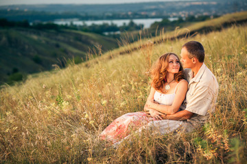 Cheerful couple in love sitting on the slope of ravine and embra