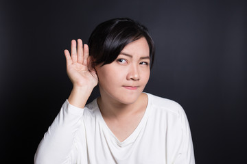 Woman with hand behind her ear and listens carefully