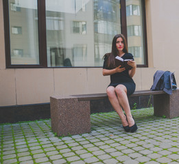 girl in black dress sitting on the bench and reads
