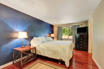 Deep blue contrast wall in bedroom with wood flooring