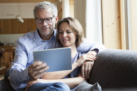 Mature couple sharing digital tablet on couch