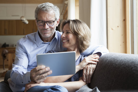 Mature couple sharing digital tablet on couch