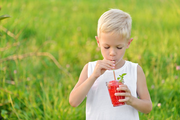 Young boy drinking a glass of red fresh juice watermelon. Summer time. Healthy lifestyle