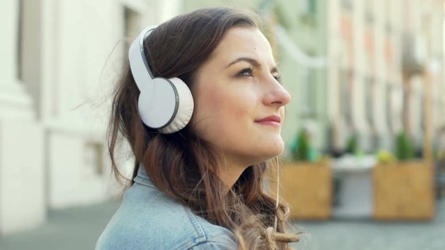 Pretty girl looking thoughtful while listening music on headphones
